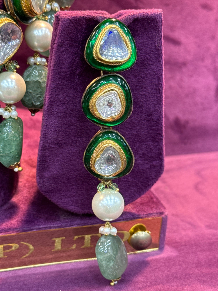 Green and gold earrings with pearl drop on a purple stand "SP. Jewellers"