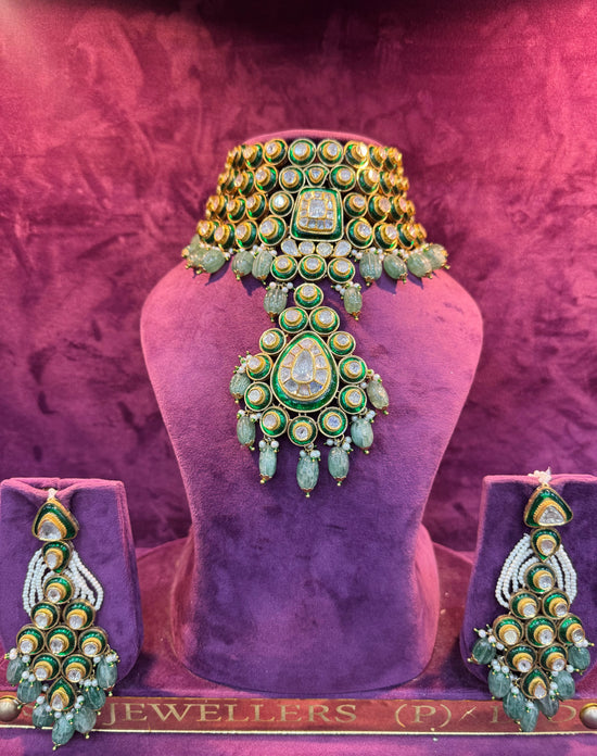 Ornate green and gold POLKI jewelry set on a purple mannequin with &