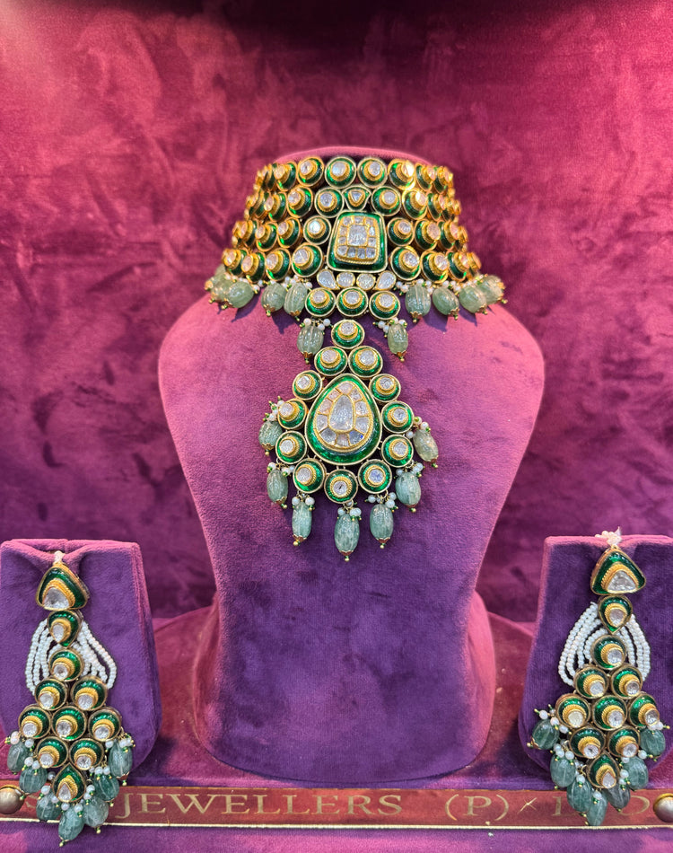 Ornate green and gold POLKI jewelry set on a purple mannequin with &