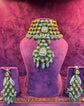 Ornate green and gold POLKI jewelry set on a purple mannequin with &