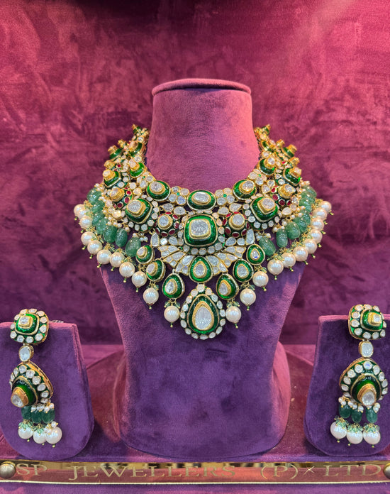 Green and gold necklace and earrings set on a purple stand with &