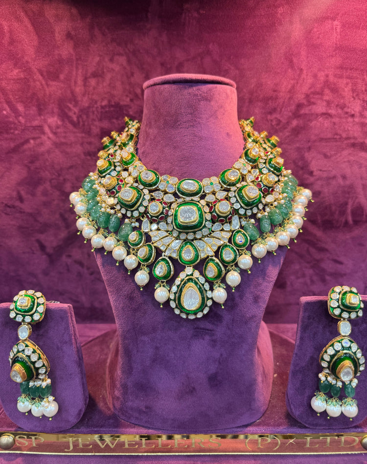 Green and gold necklace and earrings set on a purple stand with &