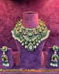 Green and gold necklace and earrings set on a purple stand with &
