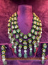 Green and gold necklace set on a purple stand with "SP. Jewellers" branding.
