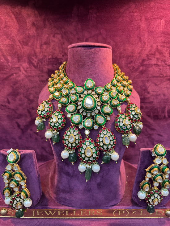 Ornate necklace and earrings set on a mannequin against a textured purple background with &
