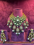 Ornate necklace and earrings set on a mannequin against a textured purple background with &