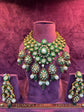 Ornate necklace and earrings set on a mannequin against a textured purple background with &