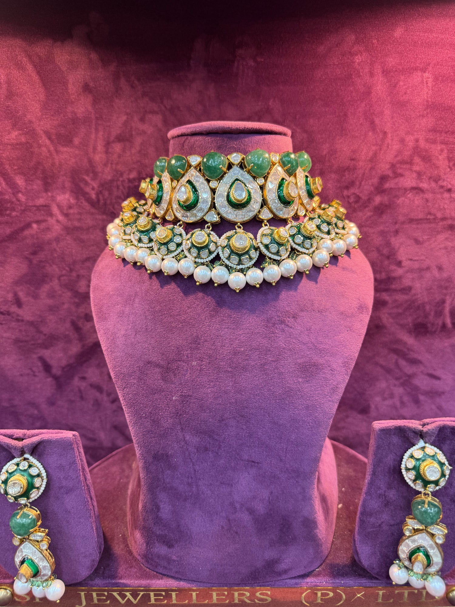 Jewelry set with green and gold elements on a purple stand with &