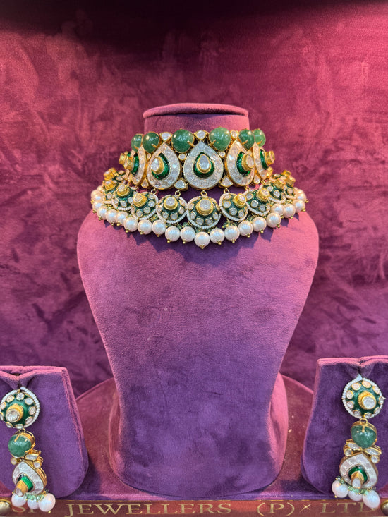 Jewelry set with green and gold elements on a purple stand with &